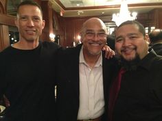 three men standing next to each other smiling