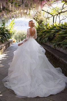 a woman in a wedding dress is posing for the camera with her back to the camera