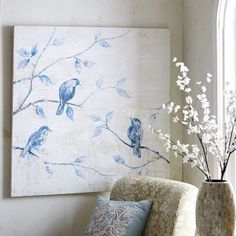 a blue and white painting sitting on top of a wall next to a vase filled with flowers