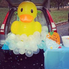 an inflatable rubber ducky sits in the back of a car with balloons