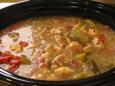 a black crock pot filled with chicken and vegetable soup on top of a table