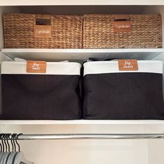 two black and white storage bins in a closet with clothes hanging on the racks