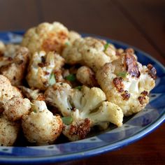 a blue plate topped with cauliflower on top of a wooden table next to an instagram post