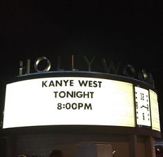 a large sign that is on the side of a building with people standing around it