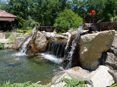 there is a small waterfall coming out of the rocks into the water in this garden