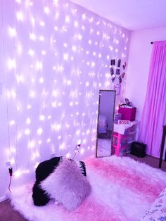 a bedroom decorated with pink and white lights, fur rugs and a mirror on the wall