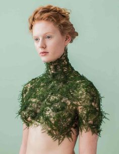 a woman with red hair and green dress on her chest is looking at the camera