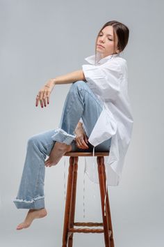 a woman sitting on top of a wooden stool with her legs crossed in the air