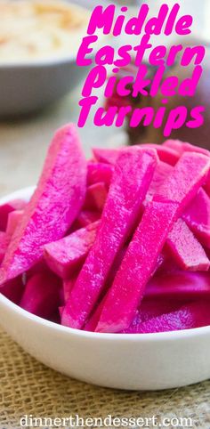 a white bowl filled with pink pickles on top of a table