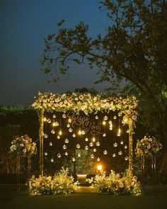 an outdoor ceremony with flowers and candles lit up at night, surrounded by greenery