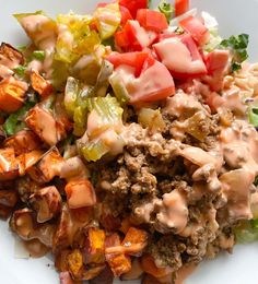 a white plate topped with meat and vegetables on top of lettuce covered in sauce