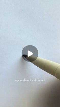 the tip of a pen that is pointing to an object on top of a white surface