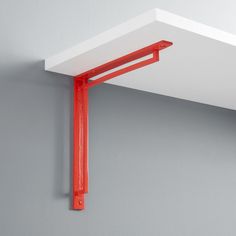 an orange metal shelf is mounted on the wall with a red plastic bracket attached to it