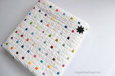 a white quilt with multicolored squares on it and a black star in the center