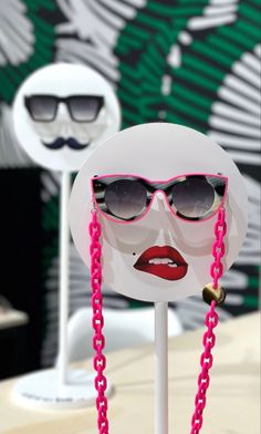 a white mannequin with sunglasses and pink chains on it's head, wearing shades