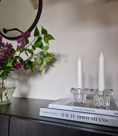 a vase filled with flowers sitting on top of a wooden table next to two candles