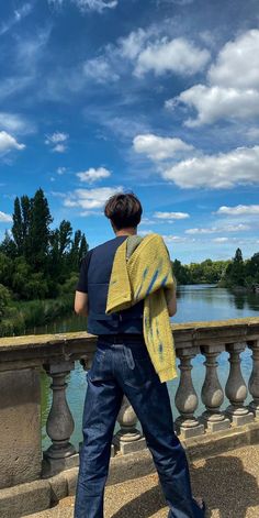 a man standing on top of a bridge next to a river under a blue sky