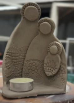 a clay sculpture sitting on top of a table next to a cup and saucer