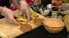 two people are making sandwiches on a cutting board with dips and condiments