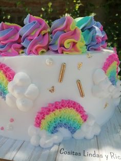 there is a cake decorated with rainbows and clouds on the top, as well as gold sprinkles