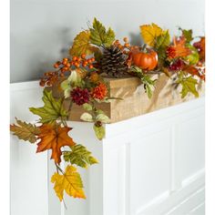 an arrangement of autumn leaves and pumpkins on a mantle