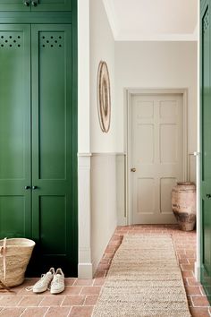 a hallway with green cabinets and shoes on the floor next to a rug in front of it