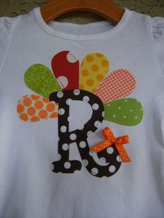 a child's shirt with the letter d on it, decorated with polka dots