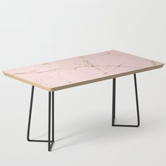 a pink table with black metal legs and an abstract design on the top, against a white background