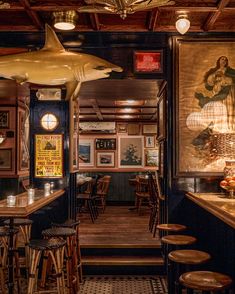 the inside of a restaurant with wooden tables and stools, artwork on the walls