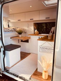 the interior of a camper van with its door open to show kitchen and dining area