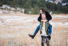 a man carrying a woman on his back in a field with snow covered mountains in the background