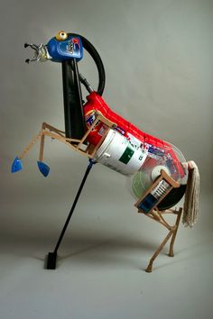 a toy insect made out of soda cans and other items on a white surface with a gray background