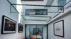 a hallway with pictures on the wall and an orange chair in the corner under glass railing