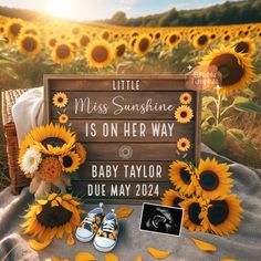 sunflowers and baby's shoes sit on a blanket in front of a sign that says, little miss sunshine is on her way