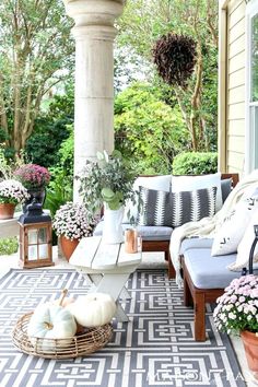 a porch decorated for fall with white pumpkins and flowers