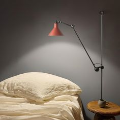 a lamp that is on top of a bed next to a table with a cup