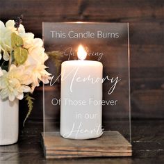 a white candle sitting on top of a wooden table next to a vase with flowers