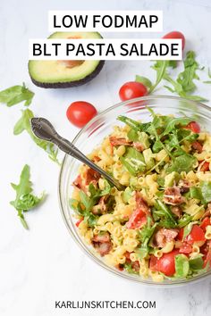 a bowl filled with pasta salad next to an avocado and tomato on the side