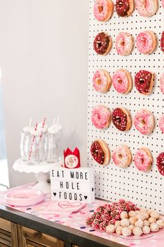 a table topped with lots of donuts next to a wall