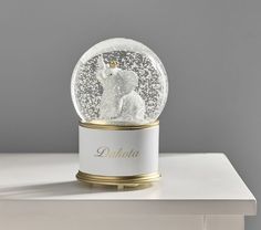 a snow globe sitting on top of a white table next to a lamp with a bear in it