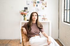 a woman sitting in a chair with her legs crossed and looking off to the side