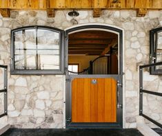 an entrance to a stone building with wooden doors and windows on either side of it