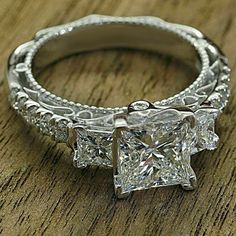 three stone princess cut diamond engagement ring with filigrees on the band and side stones