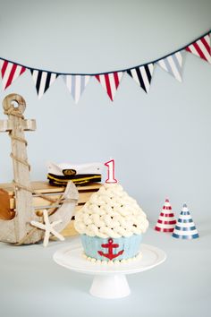 a cupcake is sitting on a cake plate with an anchor and flag banner in the background