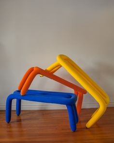 three plastic toys stacked on top of each other in front of a white wall and wooden floor