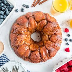 a bundt cake sitting on top of a white plate next to blueberries and raspberries