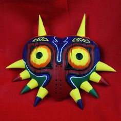 a mask with yellow horns and orange eyes on a red background