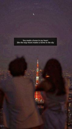 two people are looking at the city lights from top of a building with a quote written on it