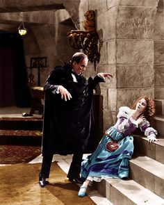 an old black and white photo of two people dressed as dracula and the woman is holding her hand out