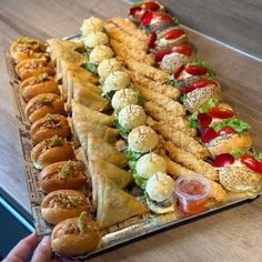 a long platter filled with different types of sandwiches and appetizers on top of a wooden table